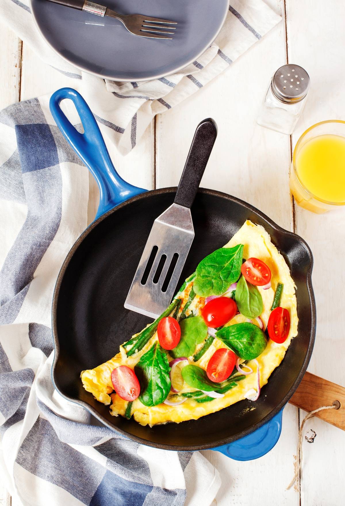 Omelette with green bean. spinach and tomato in a skillet. top view